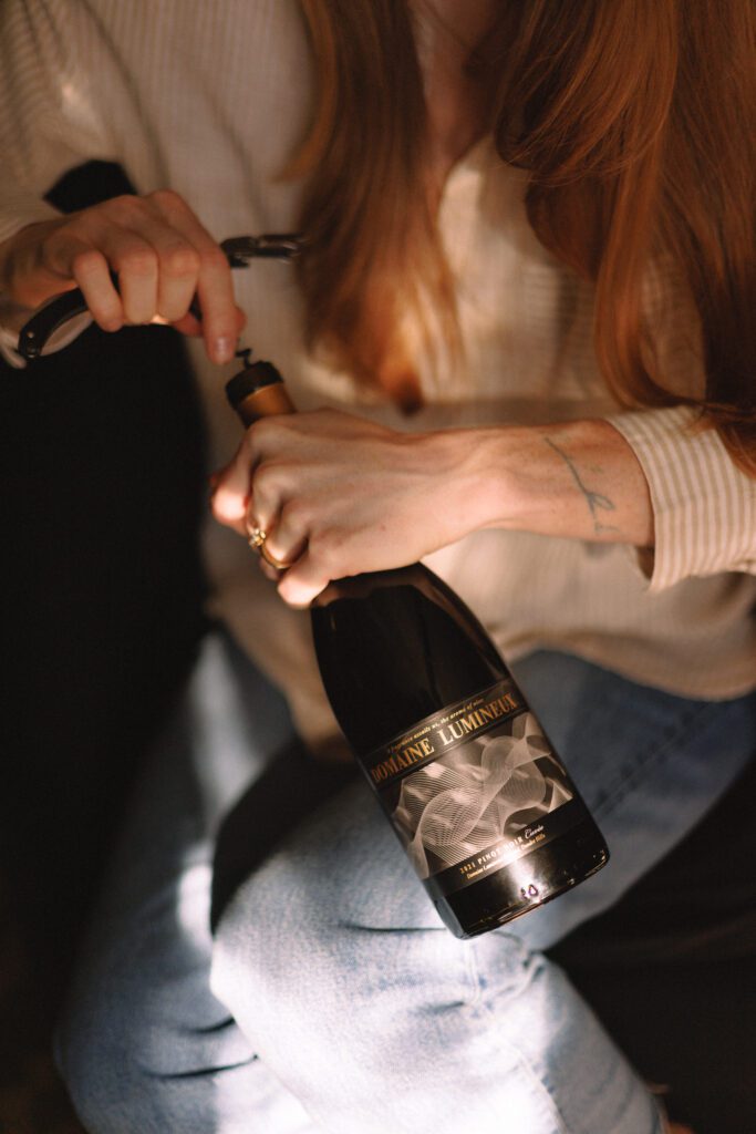 a person opening a bottle of Domaine Lumineux wine.