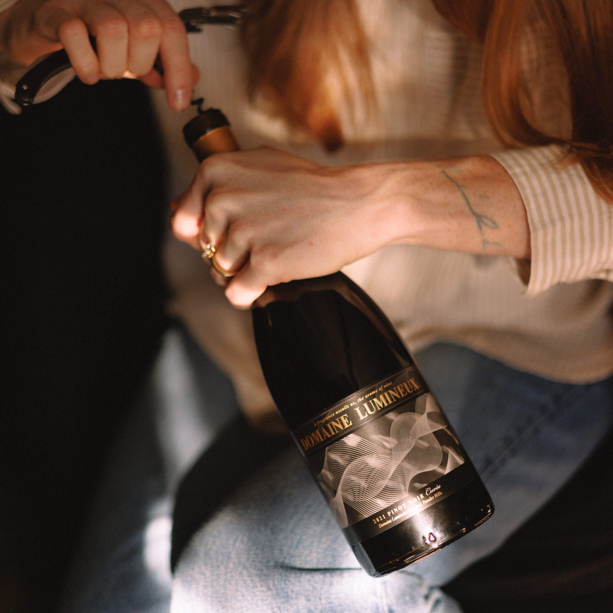 a person opening a bottle of Domaine Lumineux wine.